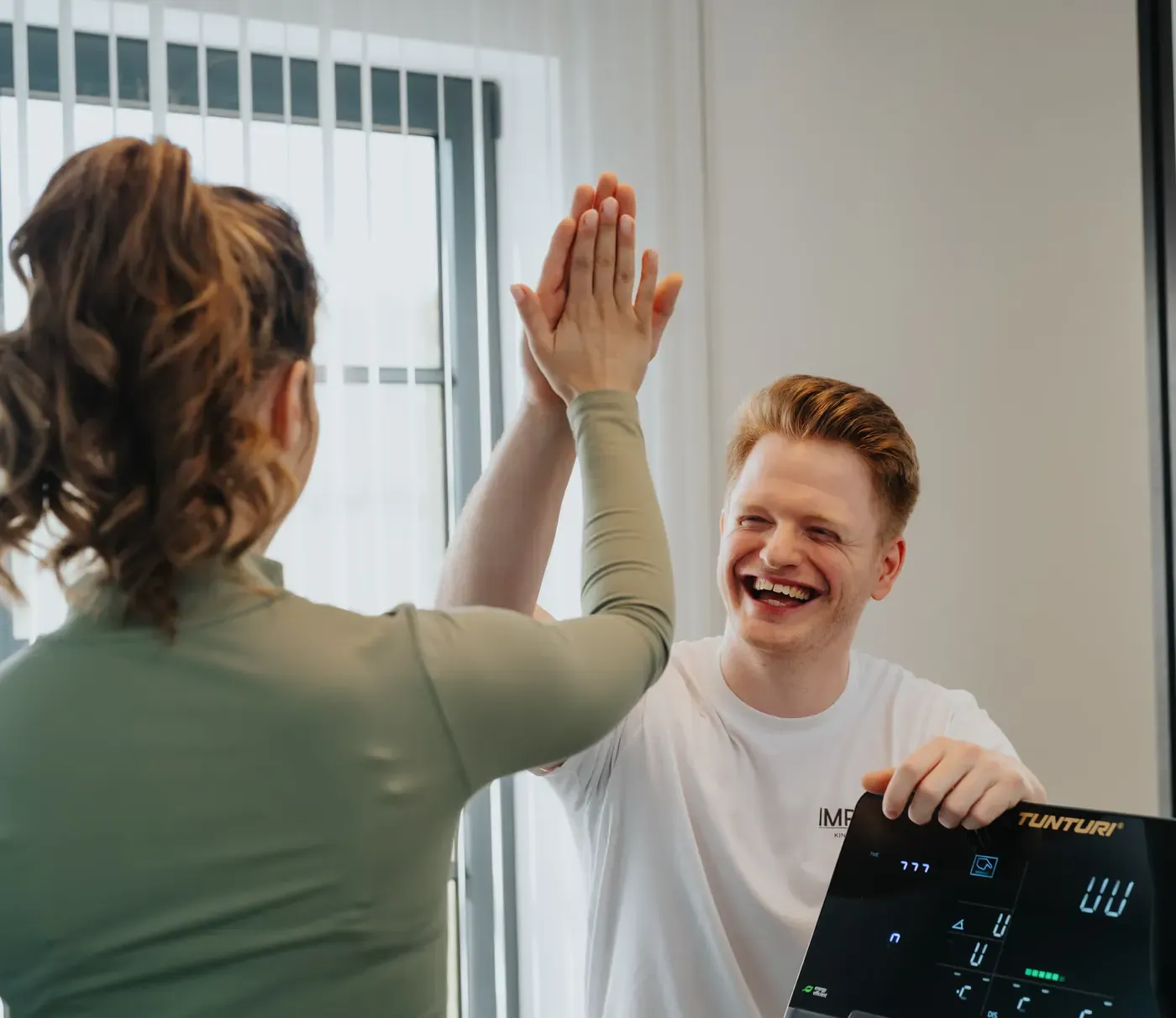 Kinesitherapeut Jasper Linders geeft een patiënte een high five na een oefening