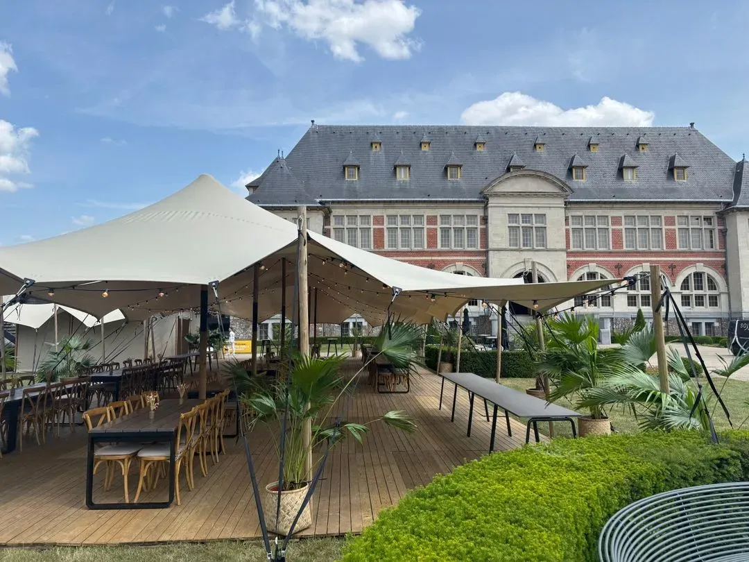 Een stretchtent van Soirée met een houten vloer en lange tafels, voor een kasteel