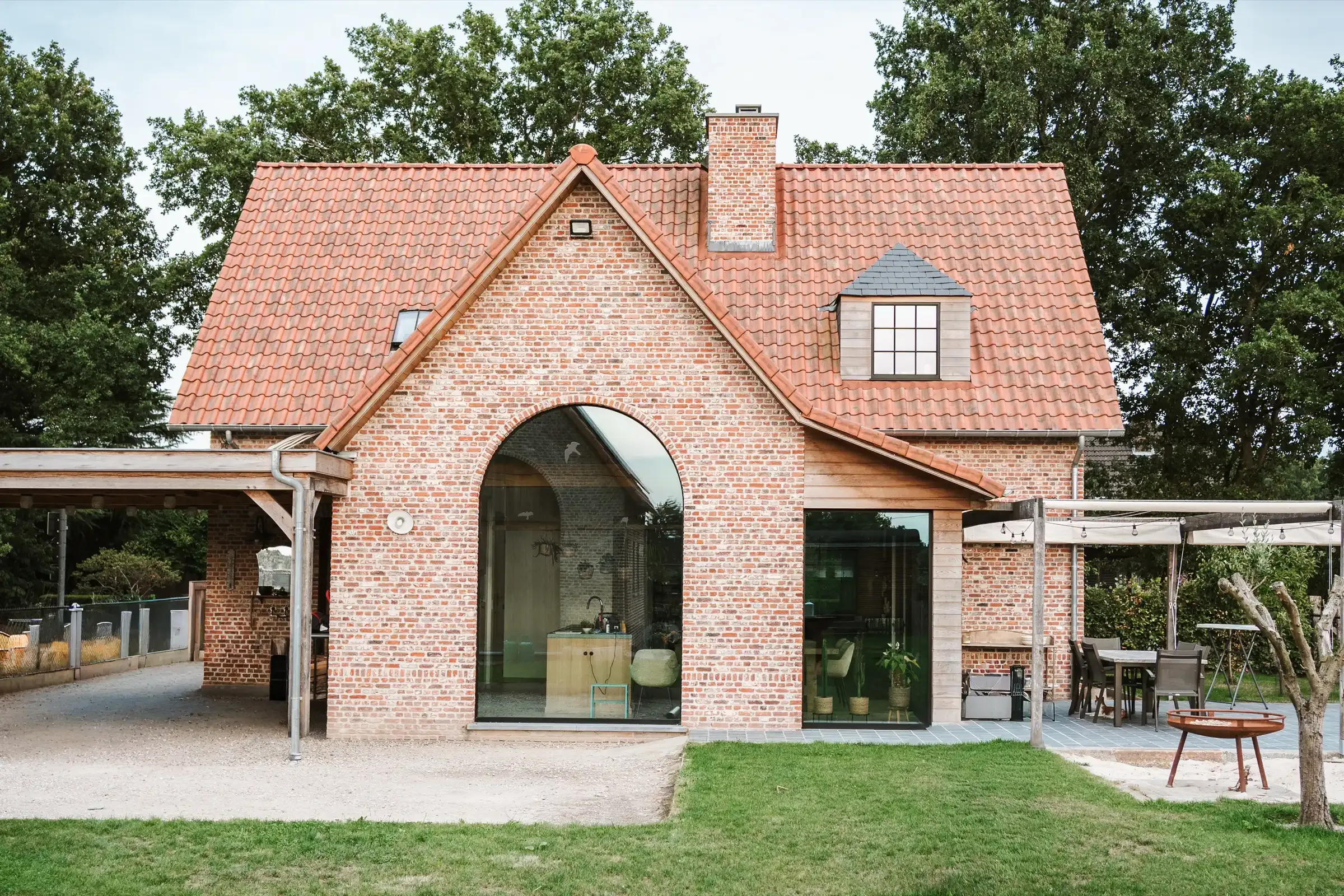 Een landelijke woning in Peer, ontworpen door WS Architectuur, met rode pannen en een boogvenster