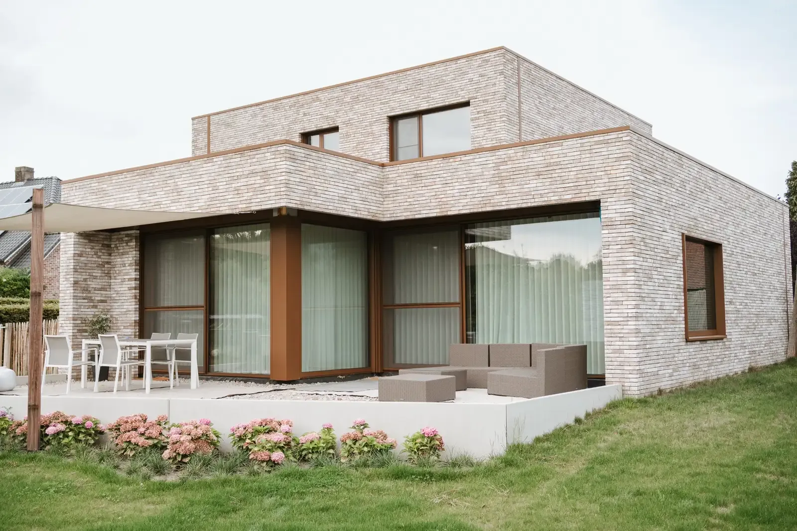 Een moderne woning in lichte baksteen in Kinrooi, met een terras onder een grote overkapping