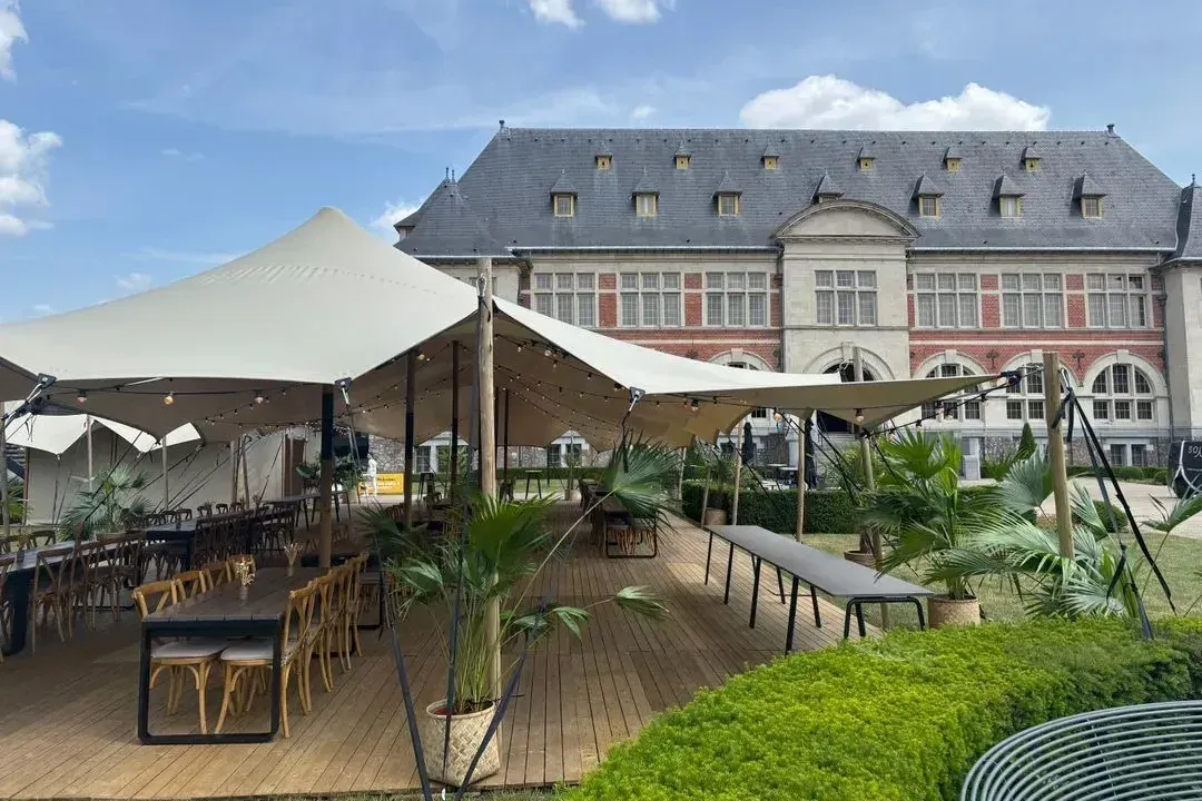 Een stretchtent van Soirée met een houten vloer en lange tafels, voor een kasteel